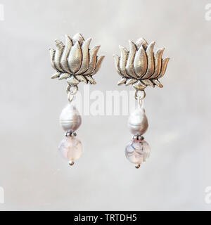 Mineral stone agate and pearl beads lotus shape earrings on neutral background Stock Photo