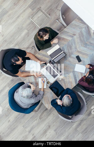 Top view of corporate business group sitting at conference table and discussing work. businessmen and businesswomen brainstorming over new project pla Stock Photo