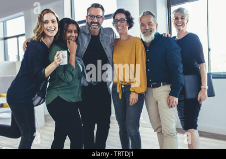 Cheerful business people standing together and laughing. Team of business professionals looking at camera and smiling. Stock Photo