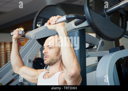Close-up of man in the gym doing dumbbell exercises to create more muscular body. Stock Photo