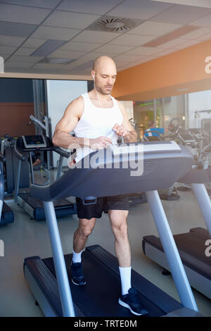 Sporty man is working out in gym. Doing cardio training on treadmill. Running on treadmill. Stock Photo
