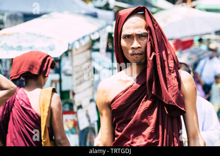 Yangon, Myanmar - March 2019: portrait of young Buddhist male novice monk at the full moon ceremony in Shwedagon pagoda temple complex. Stock Photo