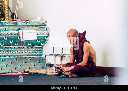 Yangon, Myanmar - March 2019: portrait of a young Buddhist male novice monk sitting at the porch in Shwedagon pagoda temple complex Stock Photo