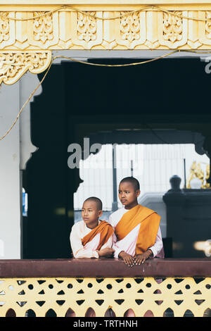 Yangon, Myanmar - March 2019: Buddhist female novice monks stand at the porch in Shwedagon pagoda temple complex. Vertical orientation. Stock Photo