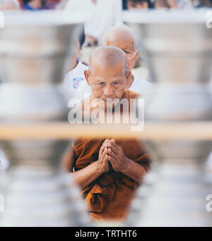 Yangon, Myanmar - March 2019: Buddhist monk prays in Shwedagon pagoda temple complex. Framing with ritual bowls. Stock Photo