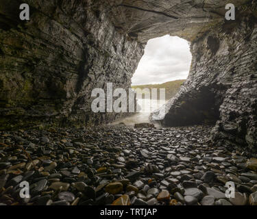 Marine cave on the ocean shore with the floor covered in polished pebbles, in Ribadeo, Galicia Stock Photo