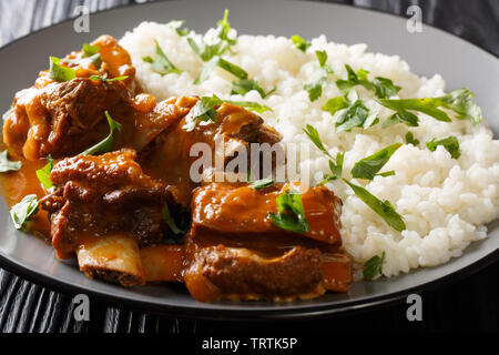 Delicious stewed ribs in a spicy sauce served with white rice close-up on a plate on the table. horizontal Stock Photo