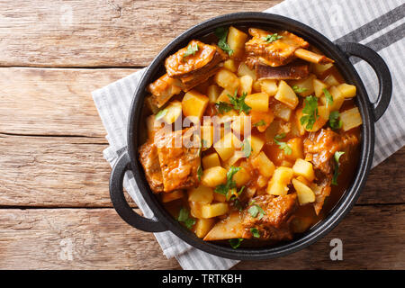 Slow cooked short beef ribs with potatoes in a spicy sauce close-up in a pot on the table. Horizontal top view from above Stock Photo