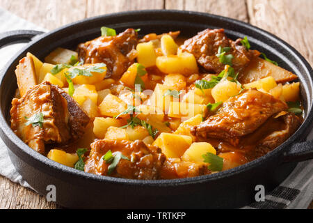 Delicious stew of short beef ribs with potatoes with gravy close-up in a pot on the table. horizontal Stock Photo