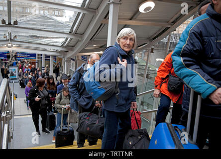 Edinburgh, UK. 12th June, 2019. Long queues of very frustrated passengers awaiting alternative transport by bus due to damage to the overhead wires between Carlisle and Lockerbie stations, all lines are blocked, Virgin Twitter feed warns 'services will be delayed as a result. Passengers require to check for updates to your journeys/services' Stock Photo