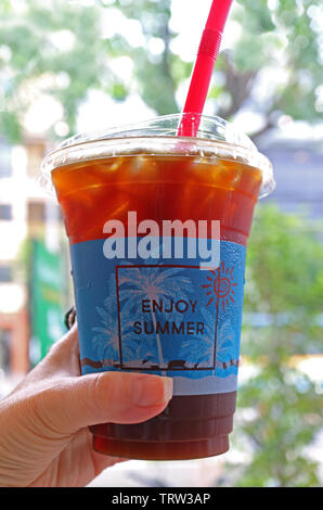 Vertical photo of iced coffee in takeaway plastic cup in woman's hand Stock Photo