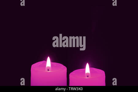 Shining a Pair of Vivid Pink Candles on Black Background with Copy Space Stock Photo