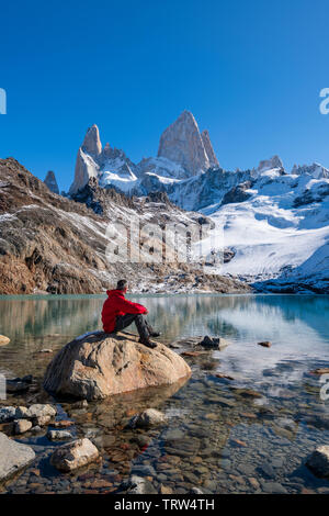 A walker sat admiring the view of Mt Fitz Roy and Cerro Torre with Lago de los Tres, El Chalten, Patagonia, Argentina.