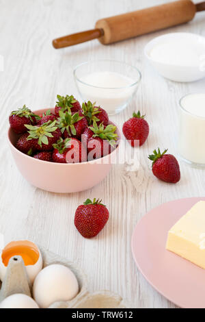 Strawberry pie ingredients: flour, eggs, butter, milk, sugar, strawberry. Side view. Cooking strawberry pie or cake. Stock Photo