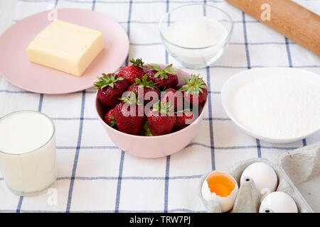 Strawberry pie ingredients (flour, eggs, butter, milk, sugar, strawberry), side view. Cooking strawberry pie or cake. Food background. Stock Photo