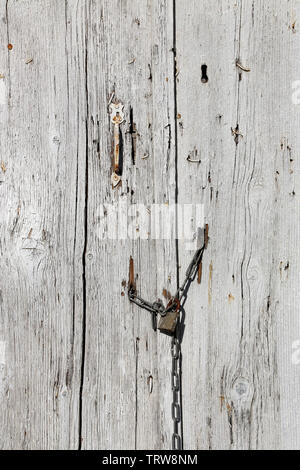 Very old wooden door with handle and padlock hanging on the chain Stock Photo