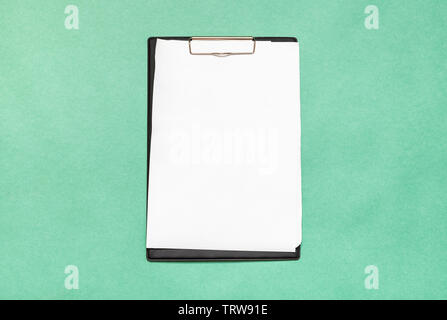 top view of clipboard with blank white paper sheets on green background Stock Photo