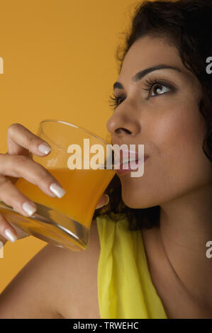 Indian woman drinking a glass of orange juice Stock Photo