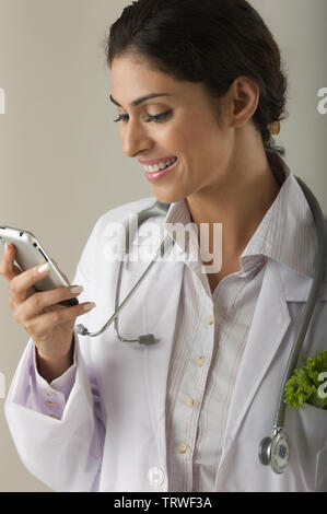 Female doctor text messaging and smiling Stock Photo