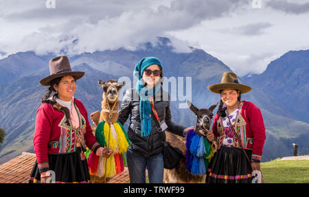 Cuzco, Peru - April 30, 2019. Peruvian women in traditional clothing with llama picturing with tourist Stock Photo