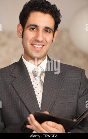 Businessman holding a personal organizer and smiling Stock Photo