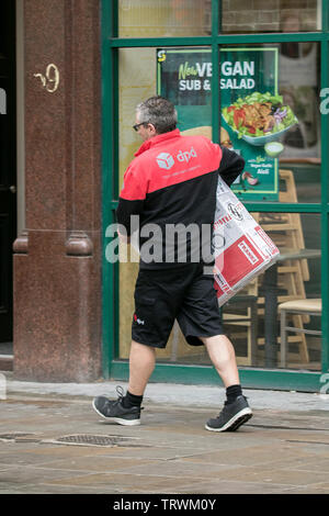 A DPD parcel courier delivery parcels to customers in Manchester city centre, UK