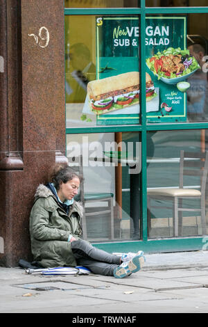 A homeless woman sleeps on the cold streets of Manchester city centre, UK Stock Photo