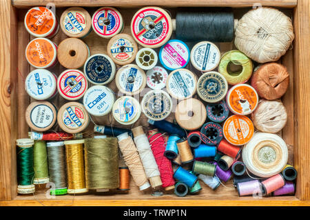 Haberdashery or sewing items stored in a drawer - reels of cotton and thread. Stock Photo