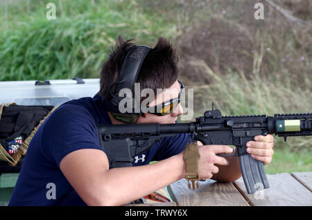 A young man takes aim with an AR-15 style rifle at a Corpus Christi, Texas USA firing range. Stock Photo