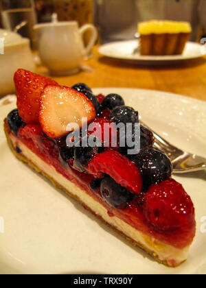 Cheesecake topped with lots of fresh strawberries, raspberries and blueberries in a cafe. Stock Photo