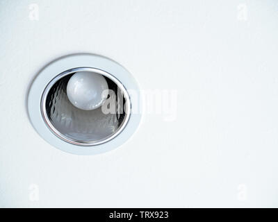 Close-up LED ceiling light. Downlight with light bulb on white ceiling background with copy space. Stock Photo