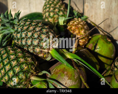 Fresh summer fruit, pineapples and coconuts on wooden background. Stock Photo