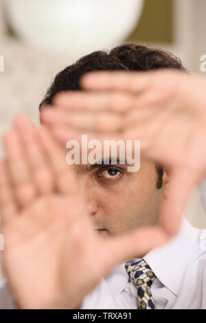 Businessman looking through finger frame Stock Photo