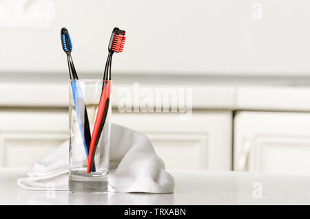 Toothbrushes in a glass and towel on the table. Selective focus. Stock Photo