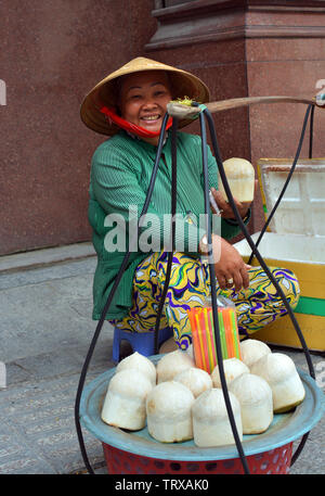 Ho Chi Minh City, Vietnam - May 30, 2019: Woman Selling Coconut Milk Drinks on the Street in Saigon. Stock Photo