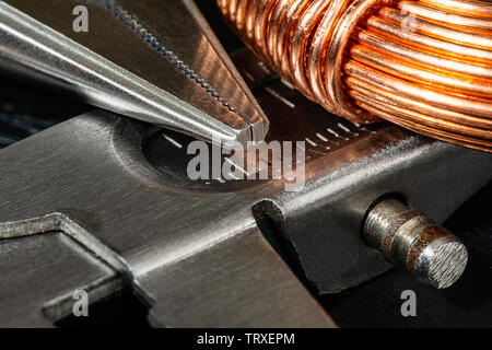 Macro Image of a coil of copper wire and a pair of needle-nose pliers.  electrician's and carpenter's Work tools and materials for the job featured to Stock Photo