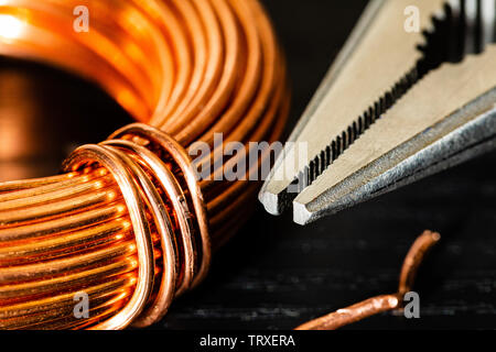 Macro Image of a coil of copper wire and a pair of needle-nose pliers.  electrician's Work tools and materials for the job featured together Stock Photo