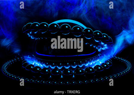 Steel balls in orbit around one another in a blue smoke with a vivid hard light from below.  A very subtle steampunk scientist is reflected in the lar Stock Photo