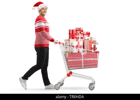 Full length profile shot of a young man with a shopping cart with presents wearing a santa hat isolated on white background Stock Photo