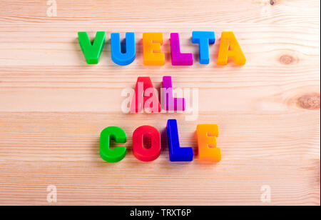 Back to school in spanish, 'vuelta al cole'. Text written with magnetic coloured letters over a wooden school table Stock Photo