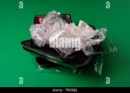 Plastic used disposable food package on green background. Plastic waste, recycle concept Stock Photo