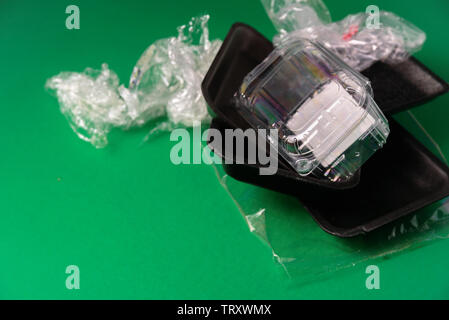 Plastic used disposable food package on green background. Plastic waste, recycle concept Stock Photo
