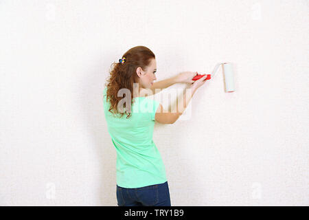 Young woman paints wall in new flat Stock Photo