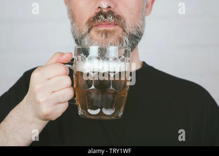man drinking beer on brick background Stock Photo
