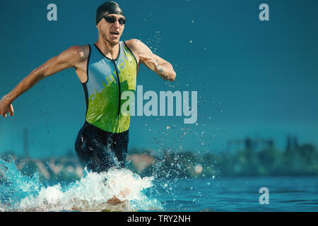 Professional triathlete swimming in river's open water. Man wearing swim equipment practicing triathlon on the beach in summer's day. Concept of healthy lifestyle, sport, action, motion and movement. Stock Photo