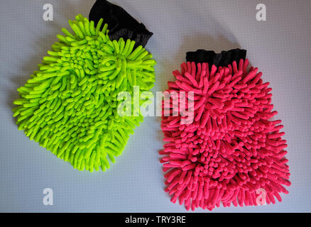 A neon yellow and a red wash mitt lying on white background in the bathroom Stock Photo