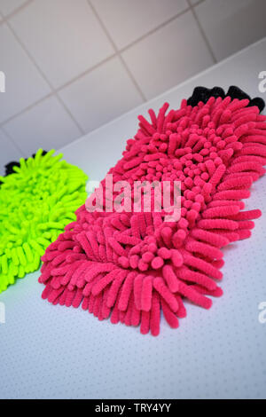 A neon yellow and a red wash mitt lying on white background in the bathroom Stock Photo