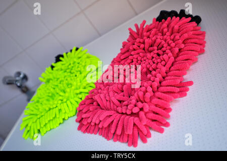 A neon yellow and a red wash mitt lying on white background in the bathroom Stock Photo