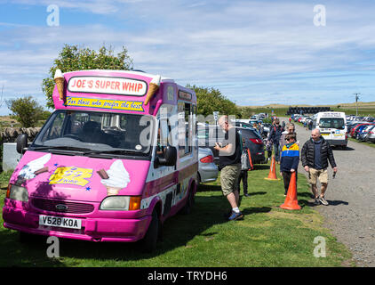 An Ice Cream Van Parked on a Grass Verge Selling Ice Cream in a Busy Holy Island Northumberland England United Kingdom UK Stock Photo