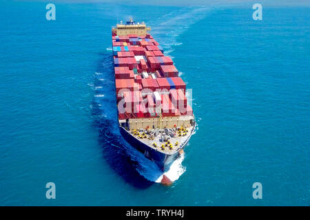 Aerial image of a large container ship at sea, loaded with various container brands. Stock Photo